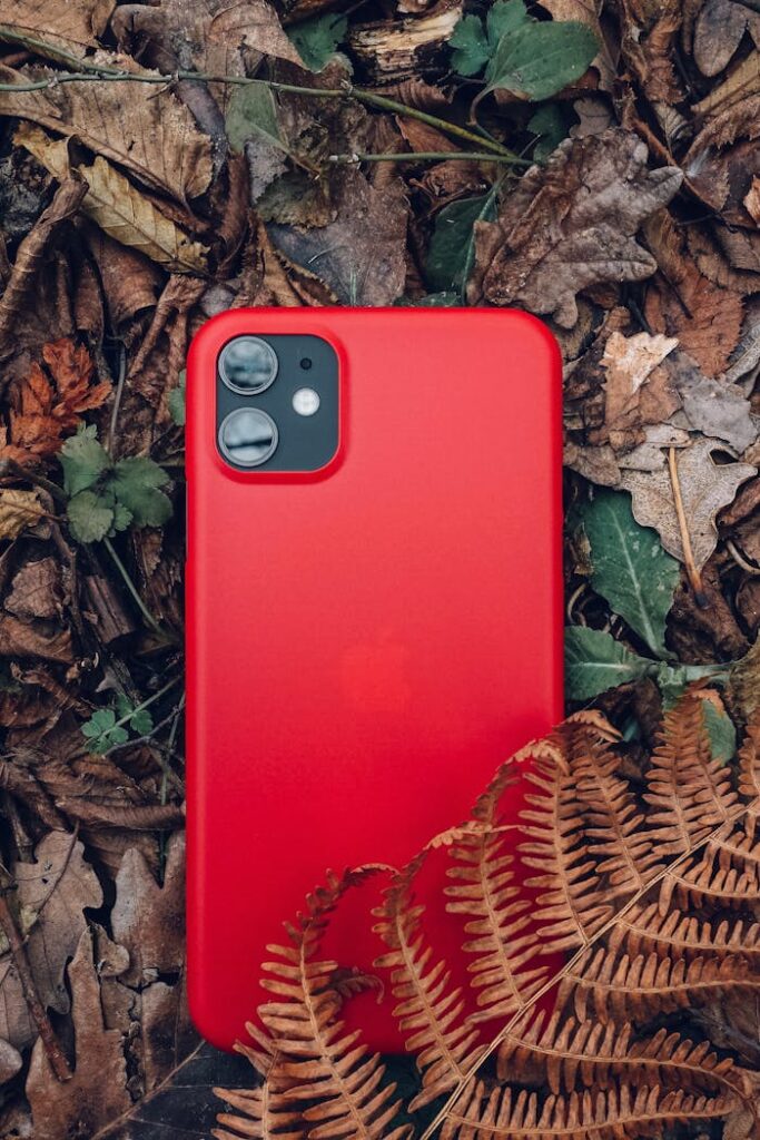 Red Smartphone on Brown Leaves